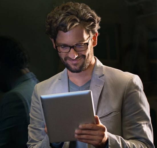 Mann mit Brille schaut in sein Tablet.